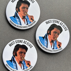 Puede incluir: Tres botones redondos blancos con una imagen en blanco y negro de un hombre cantando en un micrófono. El texto en los botones dice "Matt Stone as Elvis" y "Showroom Internationale Productions".