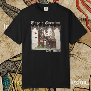 May include: Black crew neck t-shirt featuring the text "Unpaid Overtime" above a medieval illustration of a knight at a computer, with arrows. The text "1299-present" is below the image. The shirt is black.