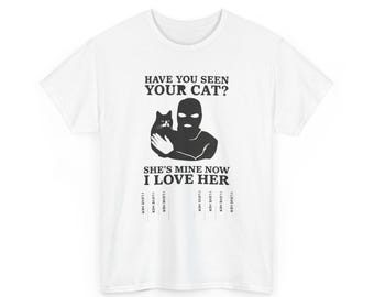 May include: White t-shirt with a graphic featuring a person in a ski mask holding a cat. Text reads "Have you seen your cat? She's mine now I love her."