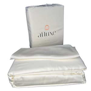 May include: A white luxury sheet set packaged in a white bag with the brand name "Atluxe" printed on it. The bag says "Luxury Sheet Set" and "100% Natural Bamboo Fiber - 400 Thread Count".