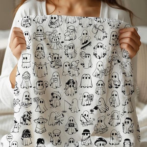 May include: White blanket featuring a repeating pattern of cartoon ghosts in various poses and costumes. The ghosts are black and white, with some holding signs or objects. The blanket is held up by a person.