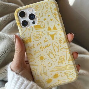 May include: A yellow and white phone case with a beach-themed design. The case features illustrations of sunglasses, flip flops, a surfboard, a seashell, and the text "Meet me at the beach".