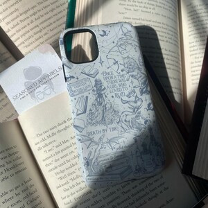 May include: A light-colored phone case with a fantasy theme, featuring illustrations of dragons, books, and the text "Once Upon a Time There Was a Girl Who Loved to Read." The case is surrounded by open books.
