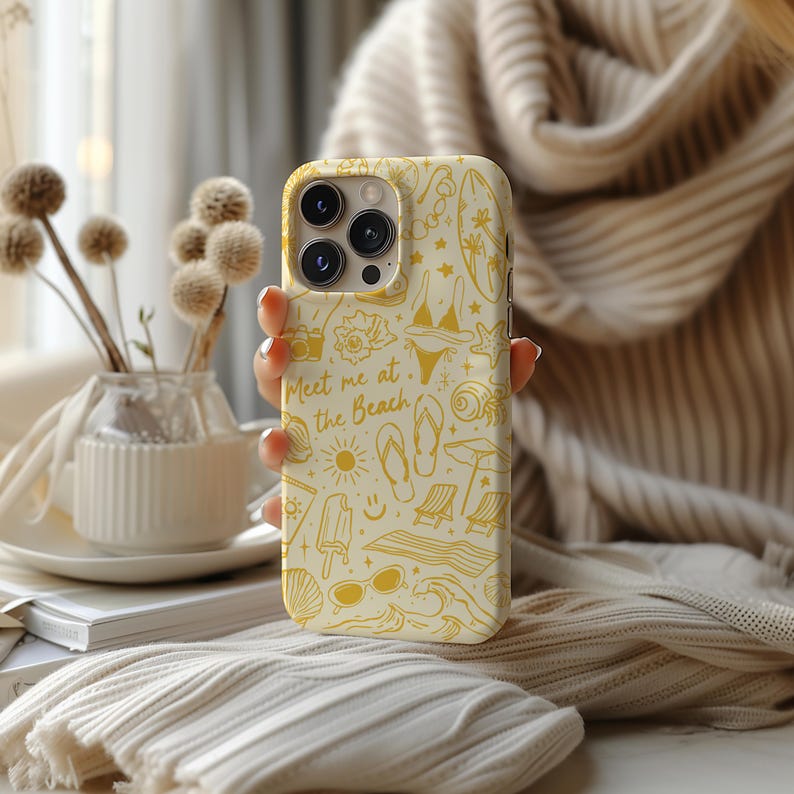 May include: A white iPhone case with a yellow design featuring beach-themed illustrations and the text "Meet me at the Beach".