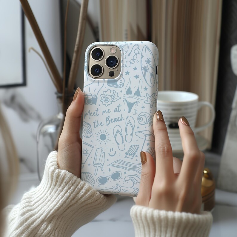 K&ouml;nnte beinhalten: Wei&szlig;es iPhone-Case mit Strandmotiv in Hellblau. Das Case zeigt Illustrationen eines Bikinis, einer Sonnenbrille, Muscheln und den Text "Meet me at the Beach."