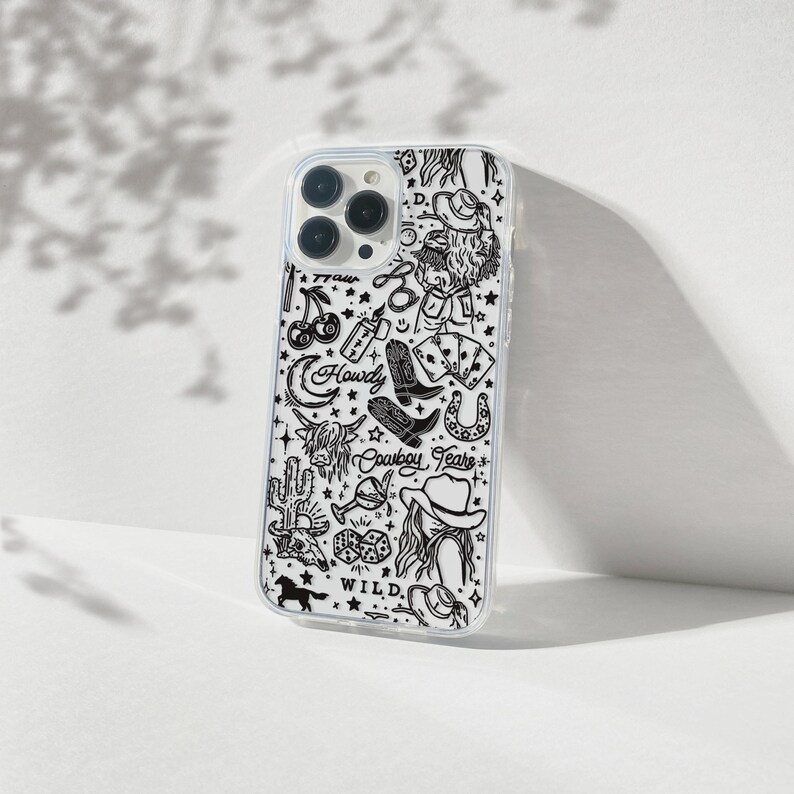 Puede incluir: Funda transparente para tel&eacute;fono con un dise&ntilde;o en blanco y negro con tem&aacute;tica de vaquero. La funda presenta ilustraciones de botas de vaquero, una herradura, un cactus y la palabra "Howdy". El dise&ntilde;o tambi&eacute;n incluye las palabras "Cowboy Tears" y "Wild".