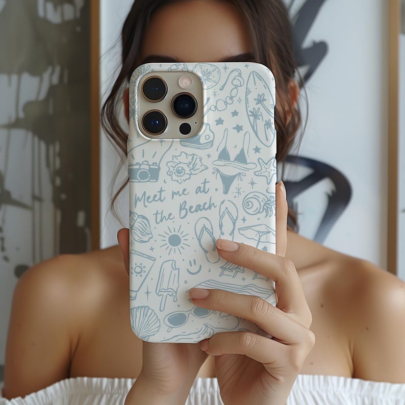 K&ouml;nnte beinhalten: Eine wei&szlig;e Handyh&uuml;lle mit einem hellblauen Strandmuster. Das Design umfasst Illustrationen von Muscheln, einem Bikini, einem Surfbrett und dem Text "Meet me at the Beach". Die H&uuml;lle wird vor einer Person gehalten.