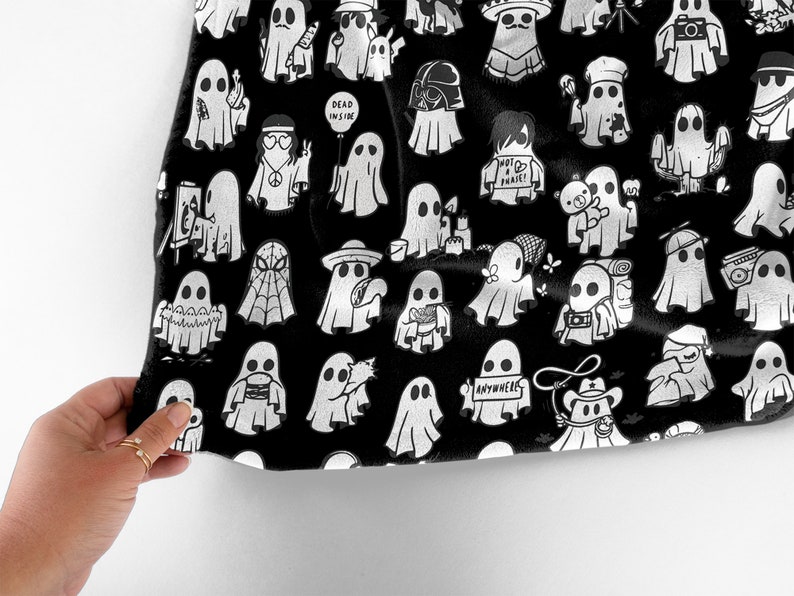 May include: Black fabric with a white repeating pattern of ghosts in various poses and with different accessories. The ghosts are wearing hats, holding cameras, and carrying signs with text like "Dead Inside" and "Anywhere".