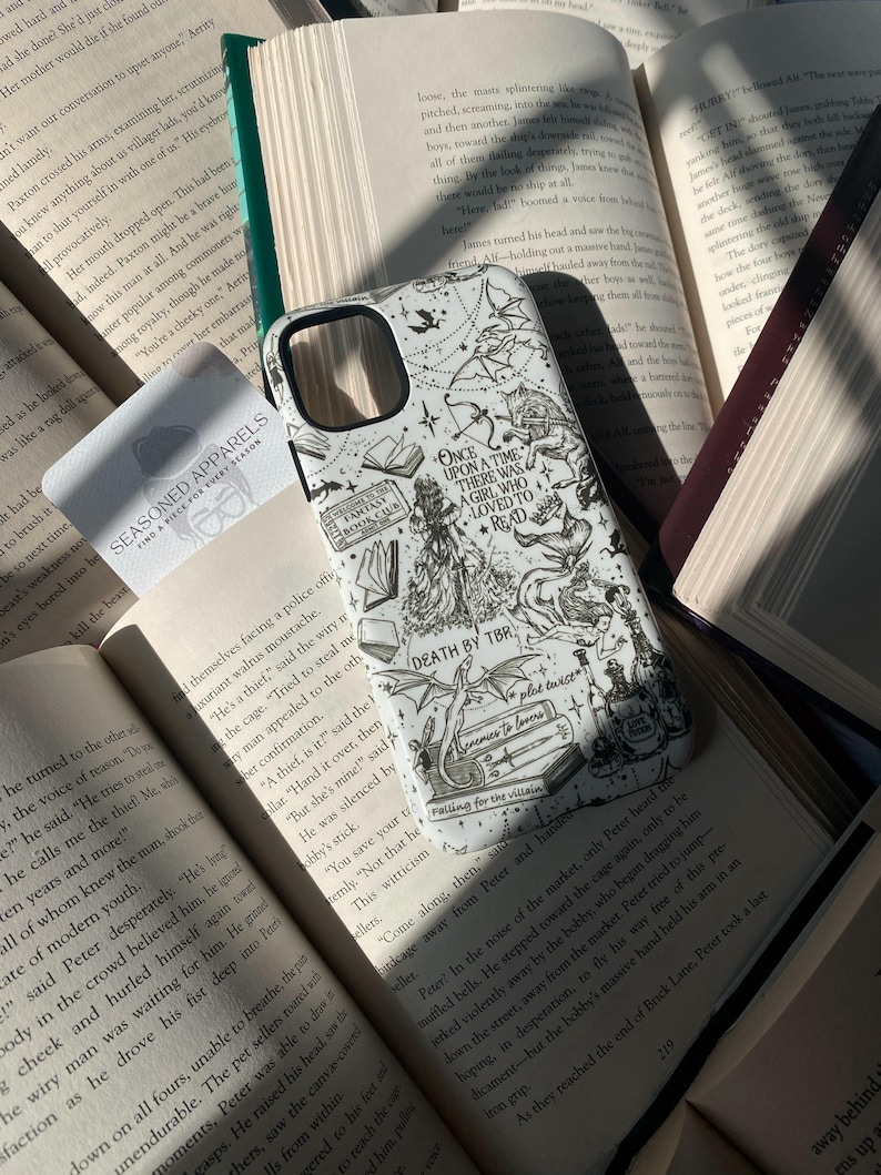May include: A white smartphone case featuring black line art illustrations of fantasy elements including a dragon, a mermaid, books, and text that reads Once Upon A Time There Was A Girl Who Loved To Read, Death By TBR, and Enemies To Lovers.