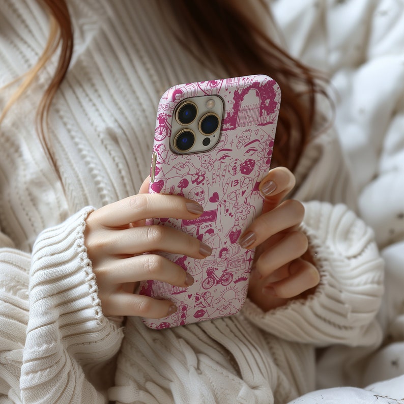 May include: A white phone case with a pink and white doodle design. The case features a variety of images including hearts, stars, dice, and a bicycle. The case has a clear camera lens.