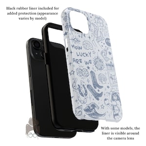 Puede incluir: Funda de tel&eacute;fono negra con una cubierta blanca con un dise&ntilde;o azul estilo tatuaje. El dise&ntilde;o incluye el texto "How Lucky Are We" junto con ilustraciones de botas, dados y una ola. Se incluye un forro de goma negro.