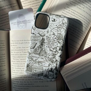 May include: A white smartphone case featuring black line art illustrations of fantasy elements, including a wolf, dragons, books, and potions. The text reads: Once upon a time there was a girl who loved to read, Fantasy Book Club, Death by TBR, plot twist, enemies to lovers, and love potion.