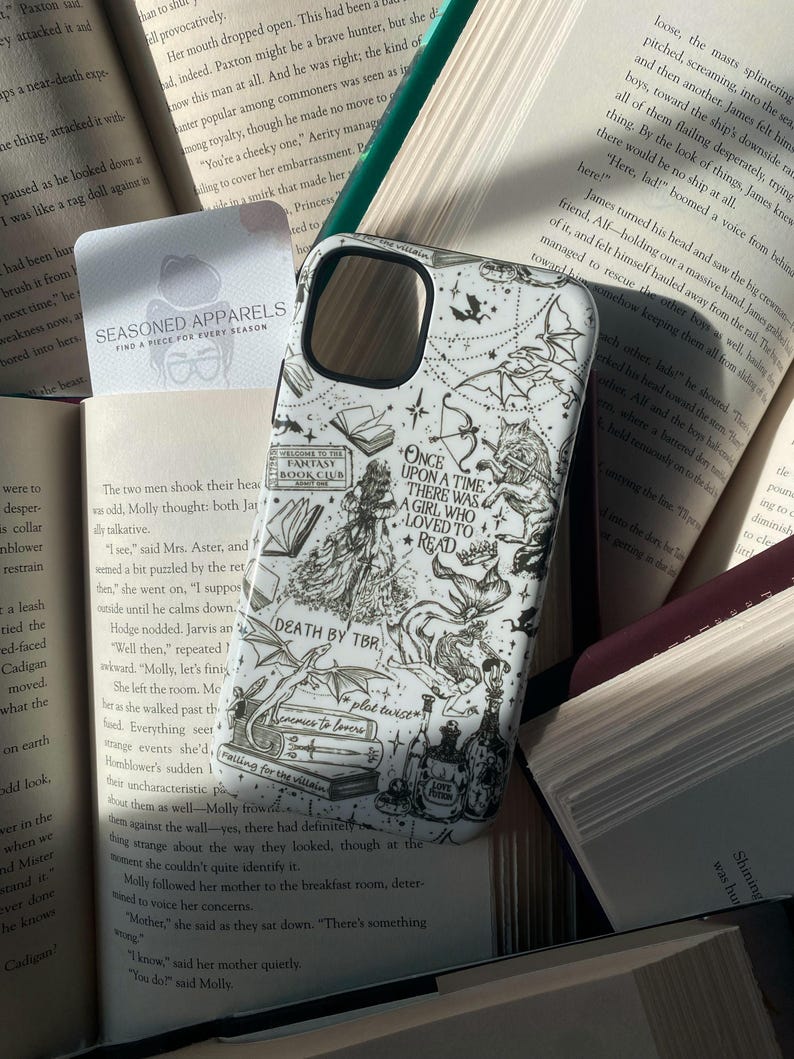 May include: A white smartphone case featuring black line art illustrations of fantasy elements, including a wolf, dragons, books, and potions. The text reads: Once upon a time there was a girl who loved to read, Fantasy Book Club, Death by TBR, plot twist, enemies to lovers, and love potion.