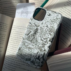 May include: A white smartphone case featuring black line art illustrations of fantasy elements, including a wolf, dragons, books, and potions. The text reads: Once upon a time there was a girl who loved to read, Fantasy Book Club, Death by TBR, and Love Potion.