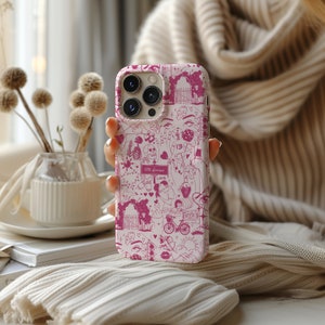 May include: A white iPhone case with a pink and white design. The design features a variety of illustrations, including hearts, flowers, and a skeleton. The text "101st Avenue" is visible on the case.