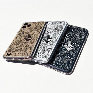 Puede incluir: Tres fundas transparentes para tel&eacute;fono con tem&aacute;tica de vaquero. Cada funda presenta un fondo de color diferente: beige, plateado y negro. Los dise&ntilde;os incluyen botas de vaquero, sombreros, naipes y las palabras "Cowboy Tears" y "WILD."