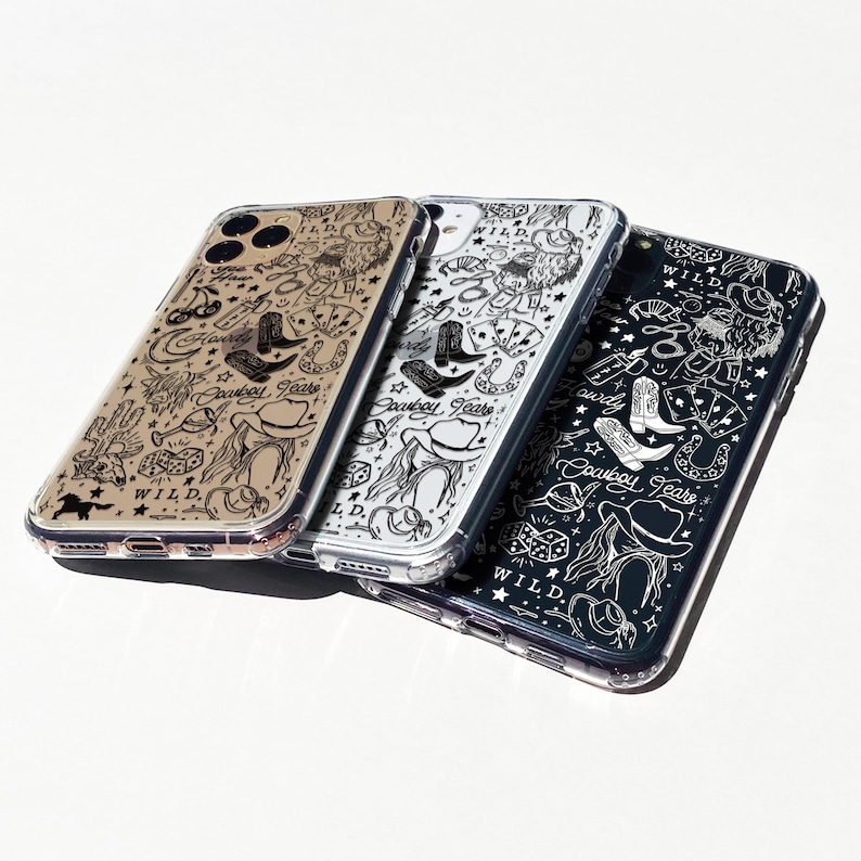 Puede incluir: Tres fundas transparentes para tel&eacute;fono con tem&aacute;tica de vaquero. Cada funda presenta un fondo de color diferente: beige, plateado y negro. Los dise&ntilde;os incluyen botas de vaquero, sombreros, naipes y las palabras "Cowboy Tears" y "WILD."