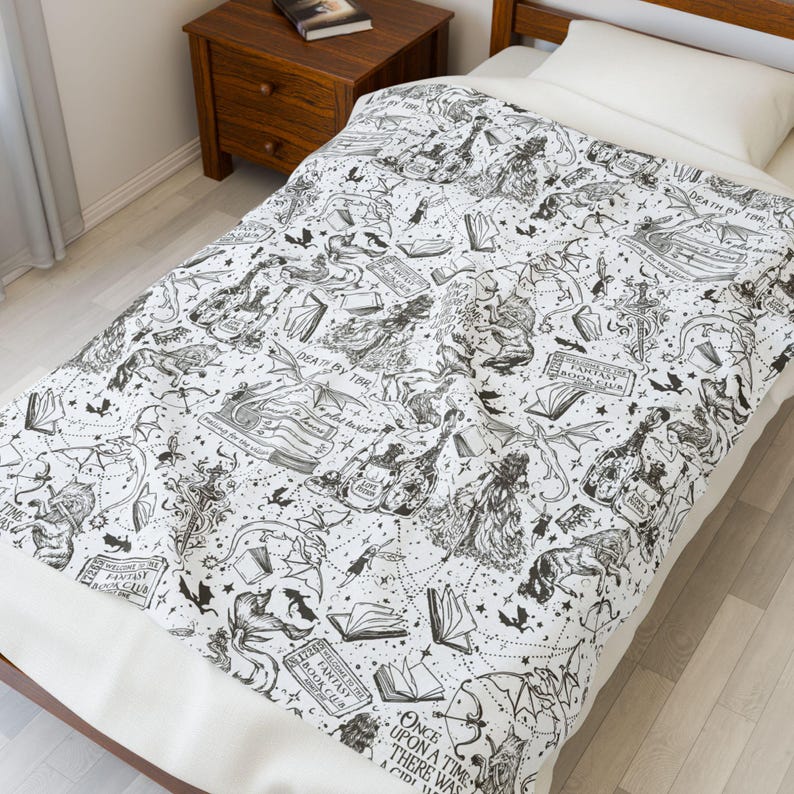 May include: Black and white bedding with a whimsical design featuring a variety of illustrations, including books, dragons, and stars. The text "Once upon a time there was a child" is visible in the lower right corner.