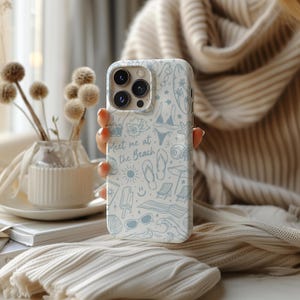 K&ouml;nnte beinhalten: Wei&szlig;es Handycase mit hellblauem Strandmuster, einschlie&szlig;lich Bildern von Bikini, Sonnenbrille und Muscheln. Der Schriftzug "Meet me at the Beach" ist auf dem Case zu sehen.