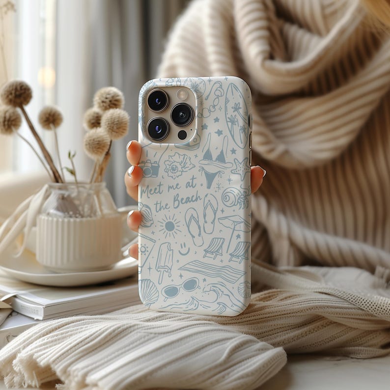 K&ouml;nnte beinhalten: Wei&szlig;es Handycase mit hellblauem Strandmuster, einschlie&szlig;lich Bildern von Bikini, Sonnenbrille und Muscheln. Der Schriftzug "Meet me at the Beach" ist auf dem Case zu sehen.