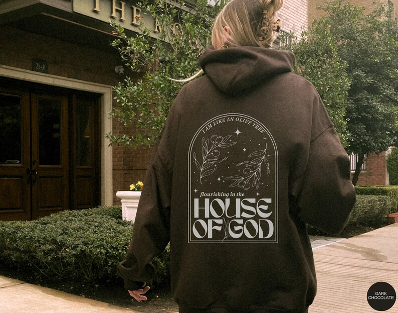 Puede incluir: Una sudadera marr&oacute;n con un gr&aacute;fico blanco en la espalda. El gr&aacute;fico presenta un olivo con el texto "Soy como un olivo que florece en la casa de Dios".