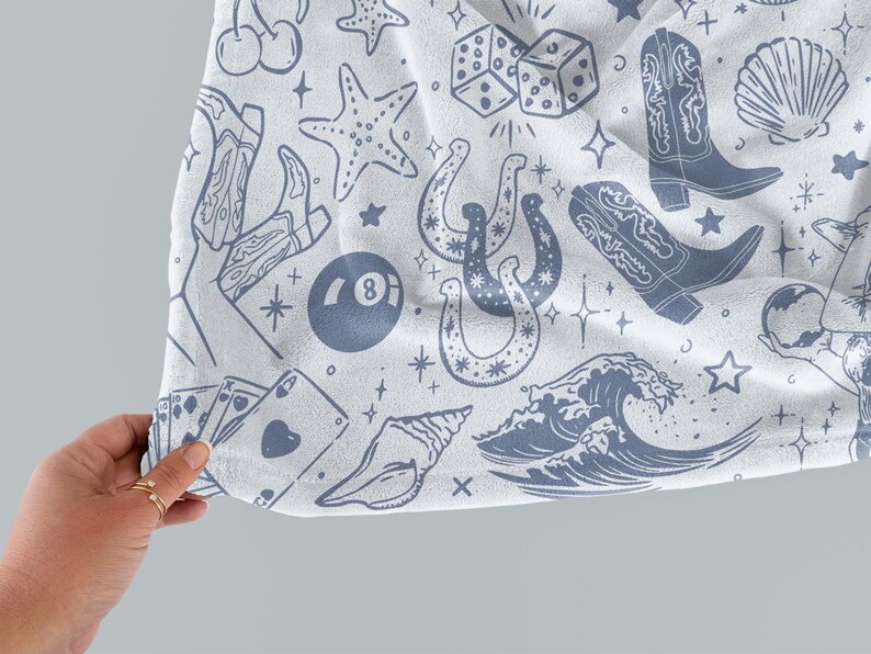 May include: A white fabric with a blue and white pattern of various symbols including a horseshoe, a seashell, a wave, a playing card, a dice, a cowboy boot, a starfish, and a 8-ball.