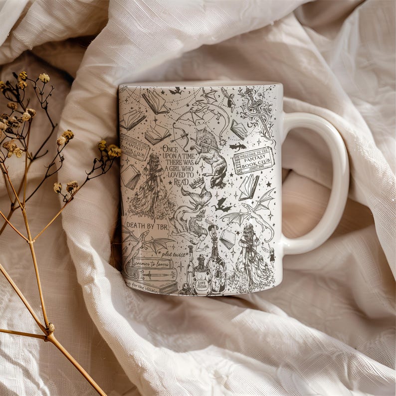 K&ouml;nnte beinhalten: Eine wei&szlig;e Keramiktasse mit einer Schwarzwei&szlig;illustration eines M&auml;dchens, das ein Buch liest, umgeben von Drachen, Flederm&auml;usen und anderen Fantasy-Elementen. Der Text auf der Tasse lautet "Once upon a time there was a girl who loved to read" und "Fantasy Book Club".