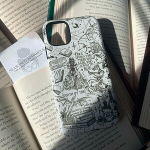 May include: A white smartphone case featuring black line art illustrations of fantasy elements, including a dragon, books, and text that reads Once Upon a Time There Was a Girl Who Loved to Read, Death by TBR, and other literary-themed phrases.
