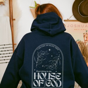Puede incluir: Sudadera con capucha azul marino con un dise&ntilde;o gr&aacute;fico blanco que representa un olivo con el texto "Soy como un olivo que florece en la casa de Dios".