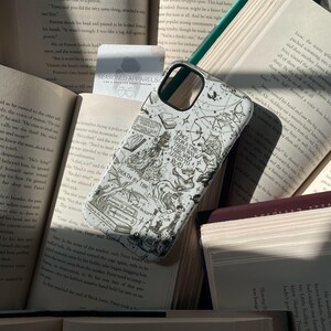 May include: A white smartphone case featuring a black ink-style illustration of fantasy motifs, including a wolf, a dragon, books, and text that reads Once Upon A Time There Was A Girl Who Loved To Read, Death By TBR, and Fantasy Book Club.
