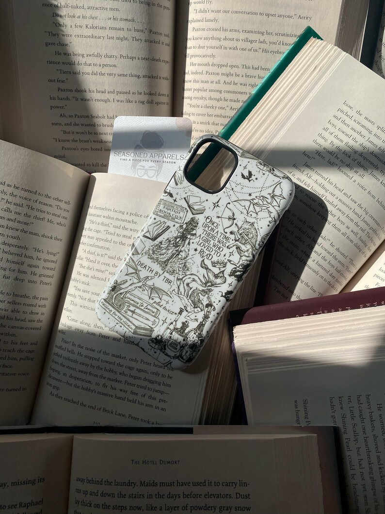 May include: A white smartphone case featuring a black ink-style illustration of fantasy motifs, including a wolf, a dragon, books, and text that reads Once Upon A Time There Was A Girl Who Loved To Read, Death By TBR, and Fantasy Book Club.