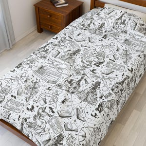 May include: A white twin-sized bed sheet with a black and white print of a fantasy book club theme. The print features illustrations of books, dragons, stars, and the text "Once upon a time there was a girl who loved to read" and "Fantasy Book Club".