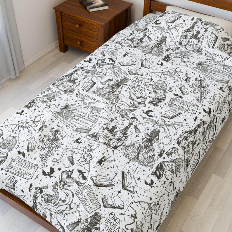 May include: A white twin-sized bed sheet with a black and white print of a fantasy book club theme. The print features illustrations of books, dragons, stars, and the text "Once upon a time there was a girl who loved to read" and "Fantasy Book Club".