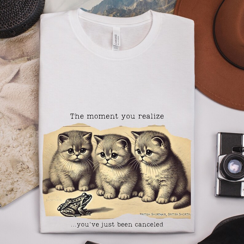 May include: White t-shirt with a humorous image of three cats and a frog. The text reads "The moment you realize... you've just been canceled."