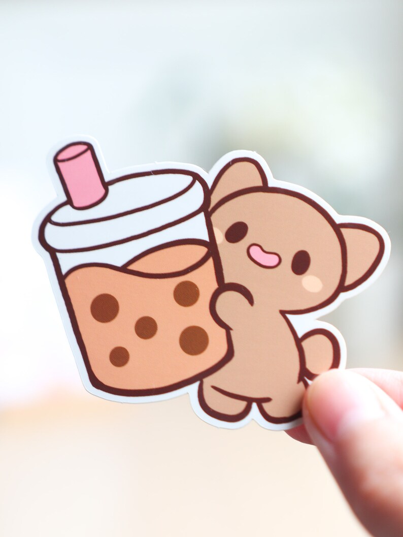 May include: A brown cartoon bear holding a brown and white boba tea cup with a pink straw.