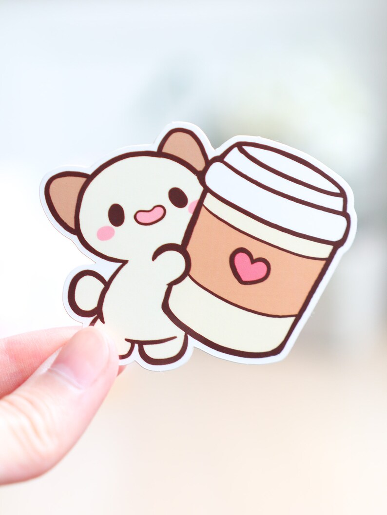May include: A white cartoon animal with brown ears holding a brown and white coffee cup with a pink heart on it.