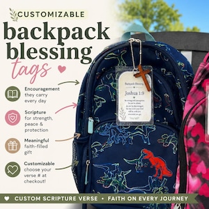 Puede incluir: Dos mochilas, una azul marino con estampado de dinosaurios y otra rosa con corazones, cada una con una etiqueta rectangular transparente en la cremallera. Cada etiqueta muestra un versículo bíblico y una pequeña cruz de madera en una cadena.