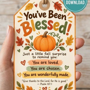 May include: A rectangular gift tag with rounded top corners and a jute twine loop. The tag features a central orange pumpkin illustration surrounded by colorful autumn leaves and hearts. Text reads: You've Been Blessed! Just a little fall surprise to remind you: You are loved. You are chosen. You are wonderfully made. Give thanks to the Lord, for He is good. Psalm 107:1.