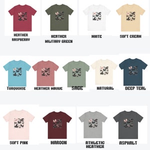 Pode incluir: Uma cole&ccedil;&atilde;o de t-shirts com uma estampa gr&aacute;fica de um chap&eacute;u de bruxa e borboletas. As t-shirts est&atilde;o dispon&iacute;veis em uma variedade de cores, incluindo framboesa mesclada, verde militar mesclado, branco, creme suave, turquesa, malva mesclado, s&aacute;lvia, natural, azul-petr&oacute;leo escuro, rosa suave, vinho, mesclado atl&eacute;tico e asfalto.