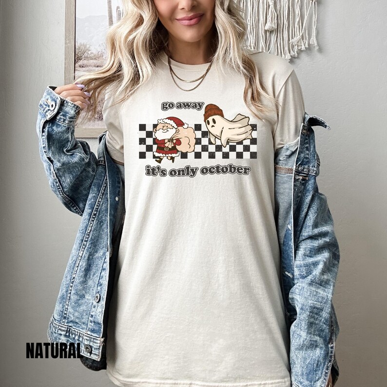May include: A white t-shirt with a black and white checkered pattern, a cartoon ghost, and a cartoon Santa Claus. The text on the shirt reads "go away it's only october".