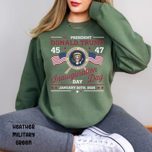 以下が含まれることがあります： 「47th President Donald Trump 45 47 Inauguration Day January 20th, 2025」の文字と、大統領の紋章と2つのアメリカ国旗が描かれた緑色のスウェットシャツ。