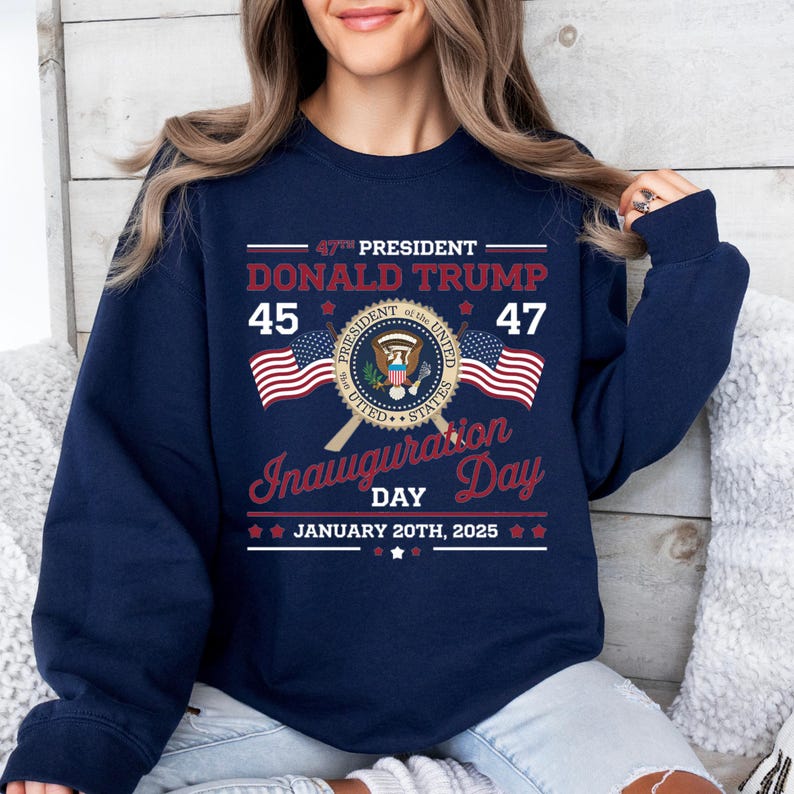 以下が含まれることがあります： 紺色の長袖スウェットシャツ。グラフィックデザインには、「47th President Donald Trump 45 47 Inauguration Day January 20th, 2025」の文字と、大統領の紋章、アメリカの国旗2つが描かれている。