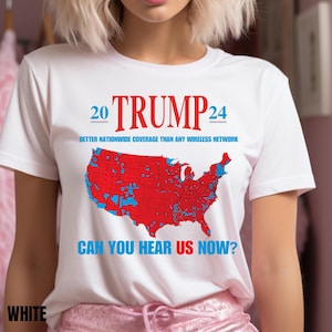 May include: White t-shirt featuring a red, white and blue graphic of the United States map. The map is divided into red and blue sections. The text "20 TRUMP 24" is printed above the map. The text "BETTER NATIONWIDE COVERAGE THAN ANY WIRELESS NETWORK" is printed below the map. The text "CAN YOU HEAR US NOW?" is printed below the map.