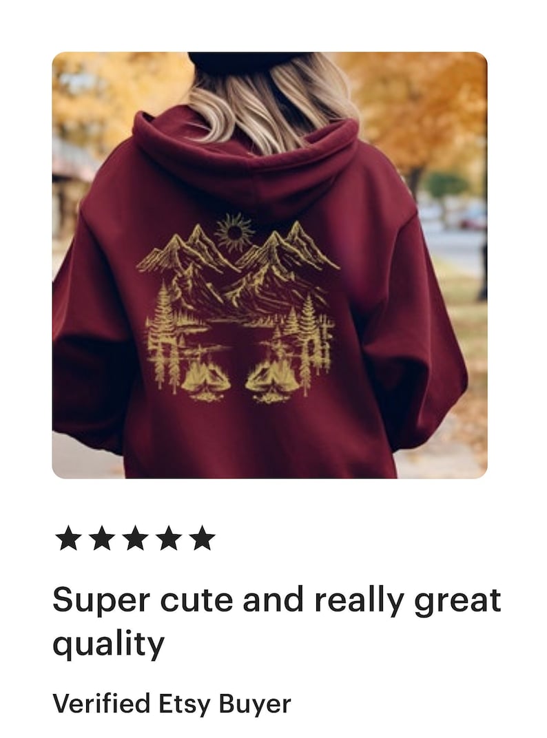 May include: A maroon hoodie with a gold mountain scene graphic on the back. The graphic features mountains, a lake, trees, and a sun.