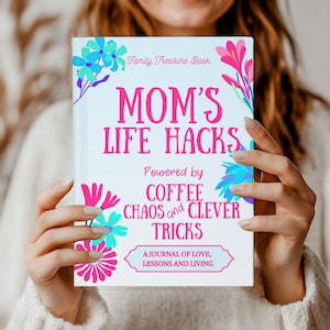 May include: A pink and blue journal with the title "Mom's Life Hacks" and the subtitle "Powered by Coffee Chaos and Clever Tricks". The journal is decorated with floral designs and the text "Family Treasure Book" is at the top.