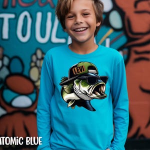 May include: Atomic blue long-sleeve shirt with a cartoon bass wearing sunglasses and a Levi hat. The shirt has a crew neck and is made of a soft material. The word "TOUL" is visible in the background.