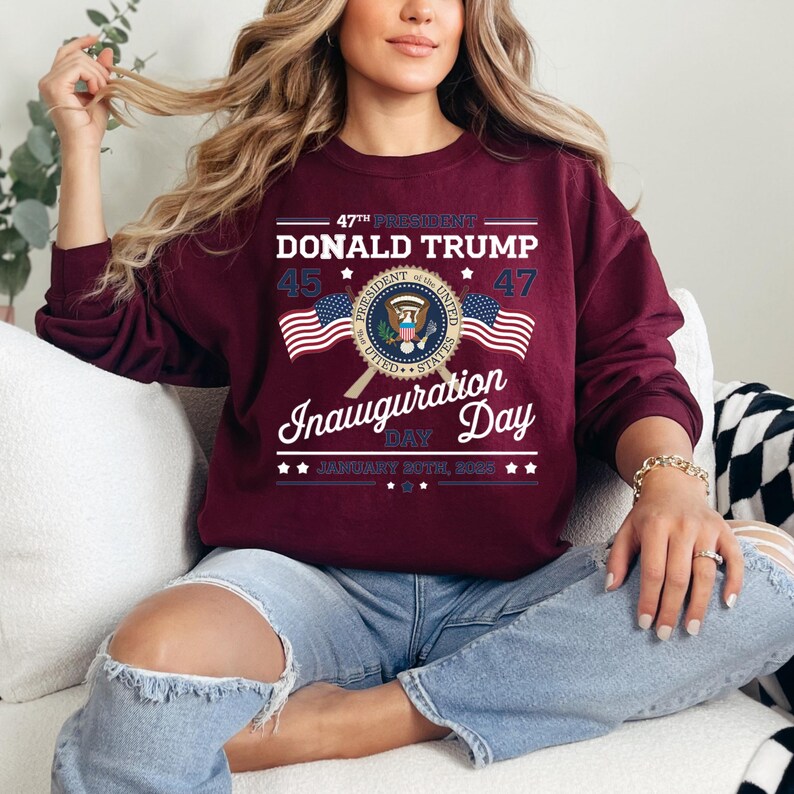 以下が含まれることがあります： 「47th President Donald Trump」の文字、大統領の紋章、そして「Inauguration Day January 20th, 2021」の文字がデザインされた、マルーンのトレーナーです。