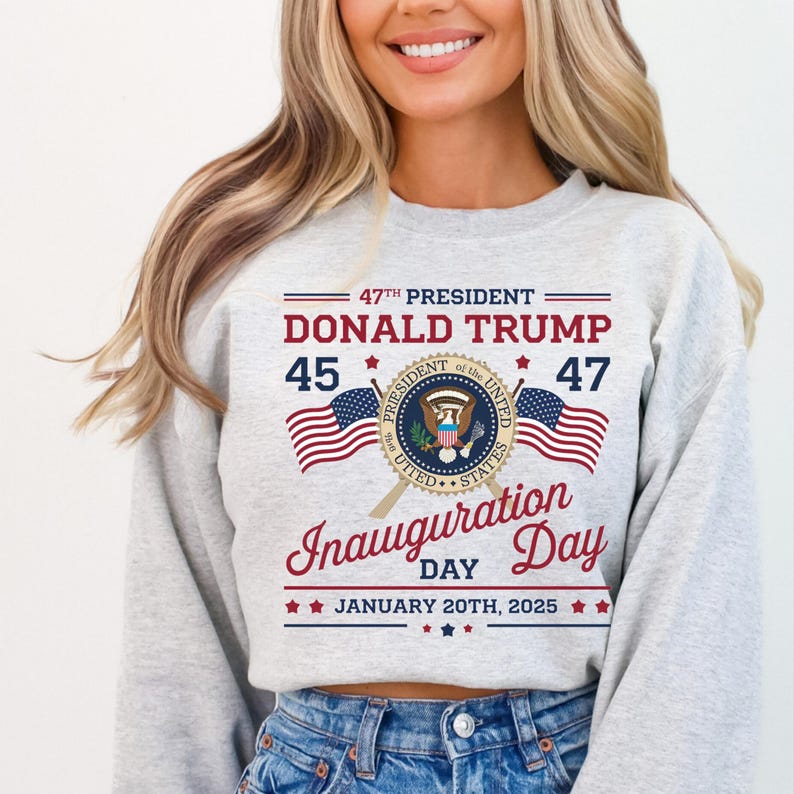 以下が含まれることがあります： 「47th President Donald Trump 45 47 Inauguration Day January 20th, 2025」というテキストと大統領の紋章が描かれた、赤、白、青のデザインのグレーのトレーナーです。