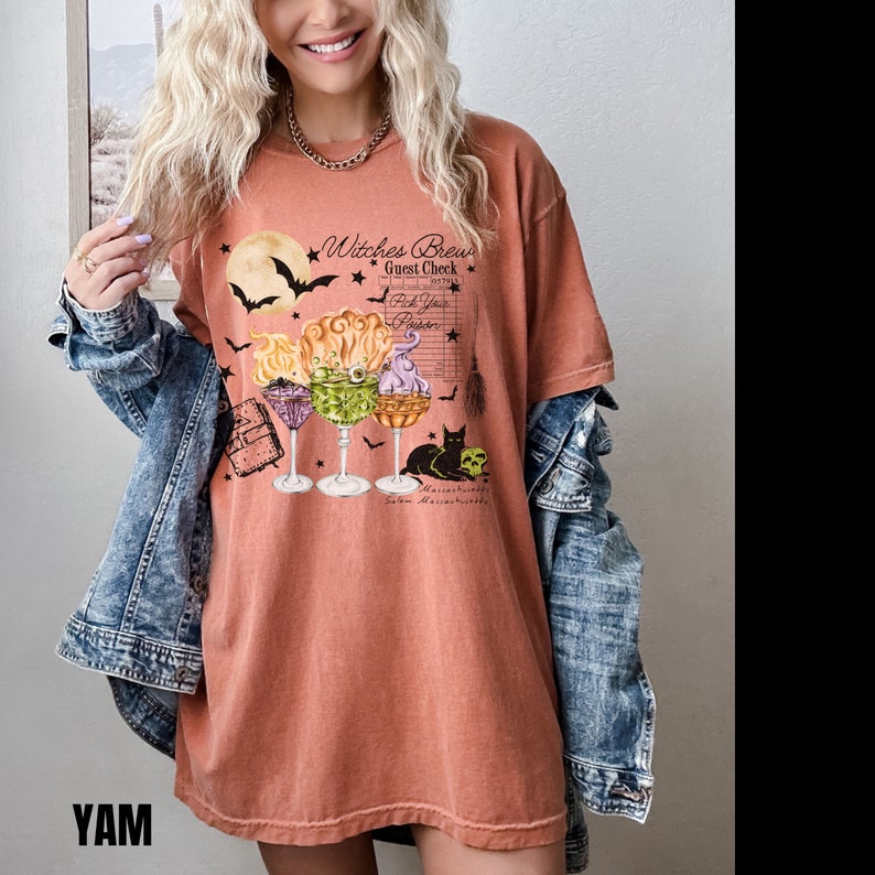 May include: A burnt orange t-shirt with a graphic of three Halloween cocktails, a black cat, and the text "Witches Brew Guest Check Pick Your Poison".