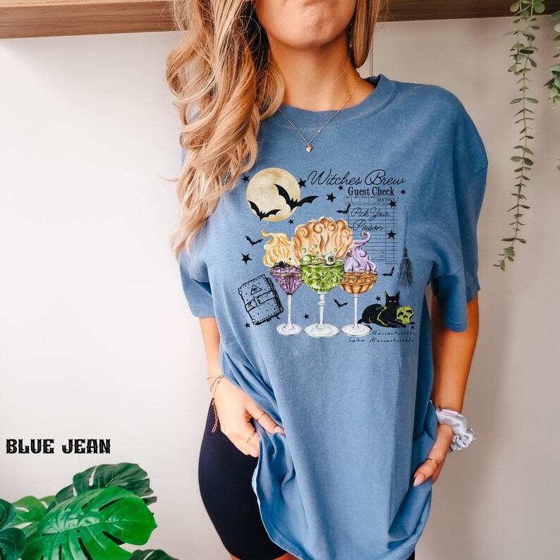 May include: A blue t-shirt with a graphic of three witches' brew cocktails, a black cat, and the text "Witches Brew Guest Check Pick Your Potion Salem Massachusetts".